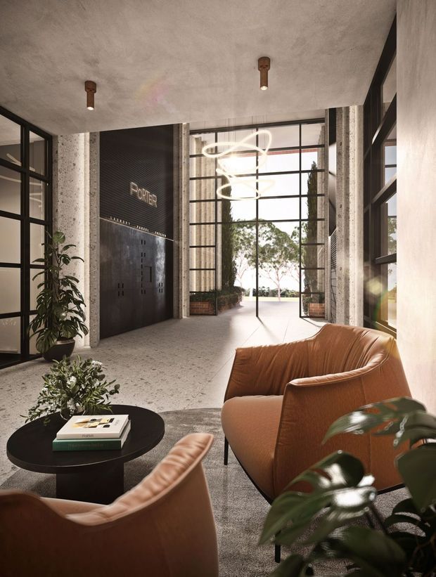 A refined commercial lobby or reception space with a high textured concrete ceiling, exposed concrete columns, black-framed floor-to-ceiling glazing, and a dramatic open entry. A dark feature wall with reception signage is paired with sculptural pendant lighting. Cognac leather lounge chairs surround a round black coffee table, with indoor plants adding greenery. The space has an industrial-contemporary character and a warm, sophisticated atmosphere.