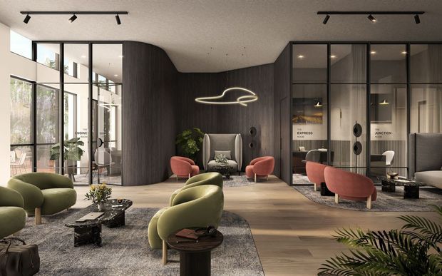 A sophisticated contemporary commercial lounge or hospitality reception area with sculptural olive-green and rust-red lounge chairs arranged over layered rugs, low dark coffee tables, and a central armchair. The space features full-height black-framed glazing, dark curved timber wall panelling and integrated glazed meeting-room partitions, with linear track lighting and a sculptural illuminated pendant. Indoor plants add greenery to the otherwise refined neutral palette.