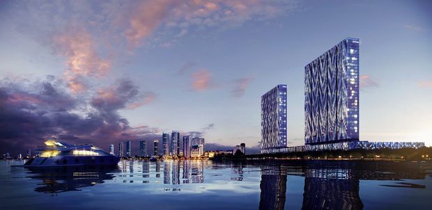 Dusk architectural visualization of a waterfront urban development, featuring two prominent illuminated high-rise towers with expressive diagonal facade patterns, a lower illuminated waterfront structure, and reflections across the calm water. The scene has a dramatic blue-purple sky and a polished contemporary commercial character.