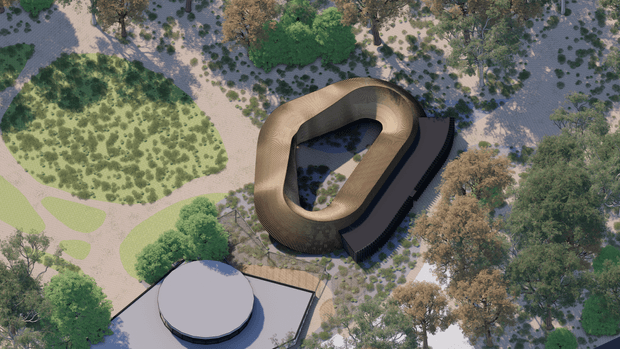 Aerial architectural rendering of a sculptural, organic ring-shaped building with a dark curved extension, set within a landscaped site of native-looking trees, planted areas, and winding pale pathways. A separate circular-roofed structure is visible in the foreground. The building has an expressive low-profile form and appears integrated into the surrounding landscape.