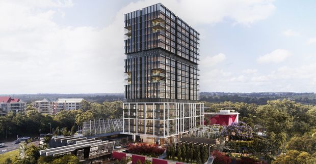 A contemporary multi-storey high-rise building with a strong rectilinear glass-and-metal facade, rising above a landscaped podium. The tower features extensive floor-to-ceiling glazing, vertical dark framing, stacked balconies or recessed terraces, and a lower podium with outdoor terraces and planted areas. The surrounding suburban landscape and neighbouring buildings are visible in the background.
