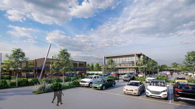 A rendered exterior view of a contemporary commercial development, showing a landscaped parking area with numerous parked cars, low-rise buildings, glass-fronted facades, trees, ornamental planting, and a prominent sign reading “...CAL SUITES.” The scene is presented in a bright architectural visualisation style beneath a partly cloudy sky.