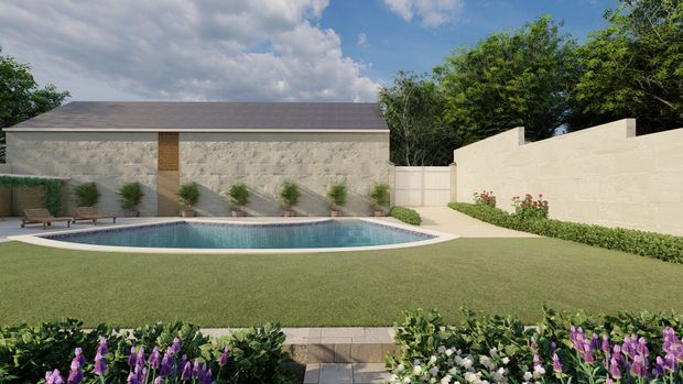 A landscaped backyard courtyard with a rectangular swimming pool, broad lawn, clipped hedges, flowering garden beds, and a low stone-clad outbuilding with a shallow pitched roof. Cream rendered boundary walls enclose the space, with a paved path leading toward the pool and dense trees beyond the walls.