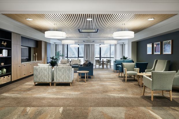 A spacious, refined contemporary lounge and reception-style interior with multiple upholstered seating areas arranged around low timber tables. The room features a broad patterned carpet, dark charcoal feature walls, pale timber built-in cabinetry and shelving, extensive glazing at the rear, and a striking slatted timber ceiling with recessed lighting and large white pendant fixtures.