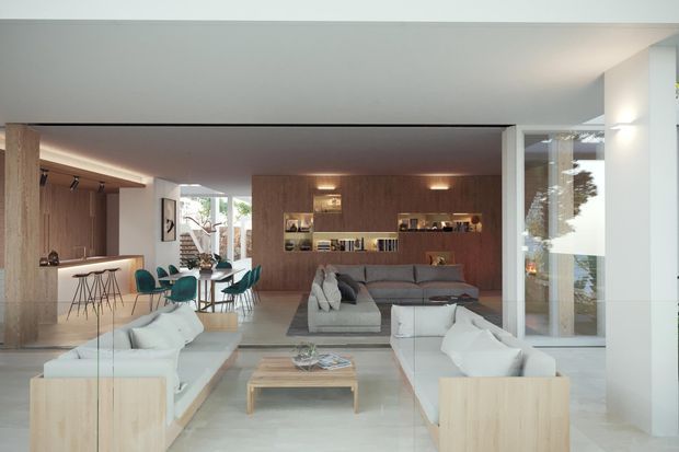 Open-plan contemporary living space with a lounge and dining area connected to a compact kitchen. The room features pale floors, white sofas, teal dining chairs, a warm timber-lined feature wall with recessed shelving and lighting, extensive glazing, and a clean low-profile ceiling.