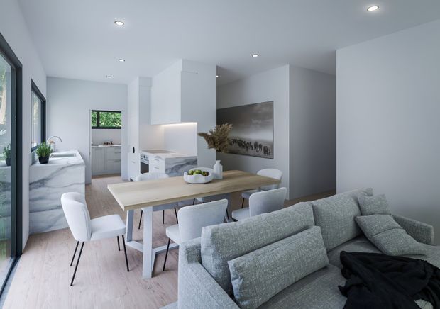 Bright open-plan interior combining a contemporary living room, dining area and kitchen. The space has pale timber flooring, white walls and cabinetry, a marble-look kitchen island and splashback, recessed ceiling lights, a light timber dining table with upholstered chairs, and a large textured grey sectional sofa. Full-height glazing along the left side brings in natural light and greenery is visible outside.