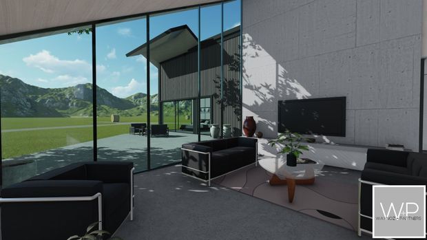 A contemporary living room with floor-to-ceiling glass walls overlooking a dramatic green mountain landscape. The space features a dark sectional sofa and matching armchairs, a low white media console with wall-mounted television, a round white coffee table with a timber pedestal base, and a large muted area rug. Grey textured wall panels and a timber-toned ceiling frame the bright, open interior, while strong sunlight creates pronounced tree shadows across the wall and floor.