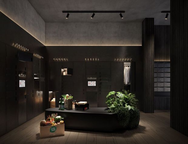 A dark, sophisticated commercial interior resembling a premium grocery or food retail space. Matte black built-in wall cabinetry and display panels line the room, with illuminated product lettering, integrated screens, and a long central dark counter or island. Potted greenery and produce boxes add organic accents. The ceiling has a smooth concrete-look finish with recessed perimeter lighting and black track lights, while the floor appears to be dark timber or timber-look planks. The overall atmosphere is moody, refined, and high-contrast.