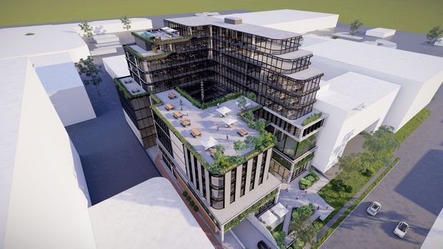 Aerial architectural rendering of a multi-storey contemporary commercial or mixed-use building in an urban setting. The design features a sculptural stepped massing, extensive dark-framed glazing, rounded corners, terraces with abundant greenery, and a large landscaped rooftop terrace with outdoor seating. Surrounding low-rise buildings, streets, and vehicles are shown as simplified context.