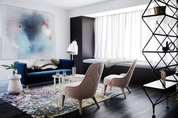 A refined contemporary living room with a deep navy channel-tufted sofa, two blush upholstered lounge chairs, a pale geometric-patterned area rug, and a white coffee table. The room features dark timber built-in cabinetry and window-seat joinery beneath sheer white curtains, a large abstract artwork, a sculptural black geometric shelving unit, and a white floor lamp. The palette combines navy, blush, white, black, and dark wood with polished, layered styling.