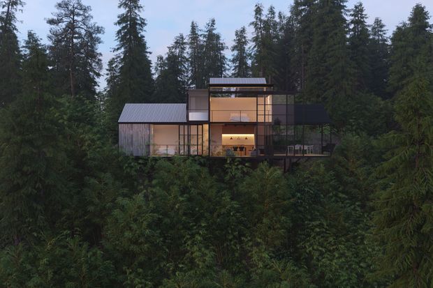 A modern multi-level house set within dense forest, viewed from outside across lush vegetation. The building has extensive floor-to-ceiling glazing, dark slender framing, several connected volumes, and corrugated metal pitched roofs. Warm interior lighting reveals living spaces and a kitchen, while elevated decks or balconies project from the structure.