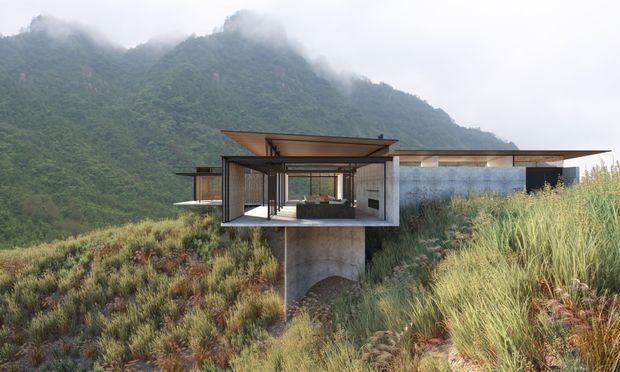 A minimalist modern house integrated into a steep, densely vegetated mountain landscape. The elevated structure has broad cantilevered flat roof planes, extensive floor-to-ceiling glazing, exposed concrete supports, dark metal framing, and warm timber soffits. Mist-covered forested mountains form the backdrop, while native grasses and low vegetation surround the building.