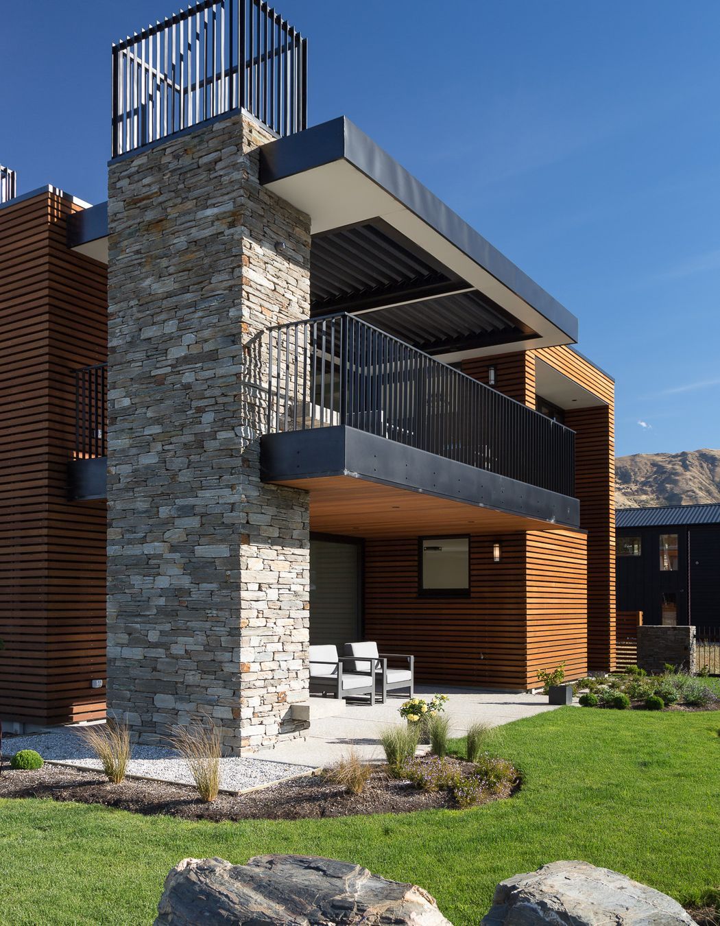 The freestanding chimney stack has been clad in local schist to visually anchor the element to the site.