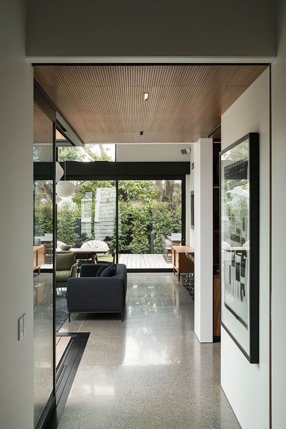 The connecting hallway creates a carefully choreographed journey between the restored villa and the contemporary pavilion, drawing visitors towards the open-plan living spaces beyond.