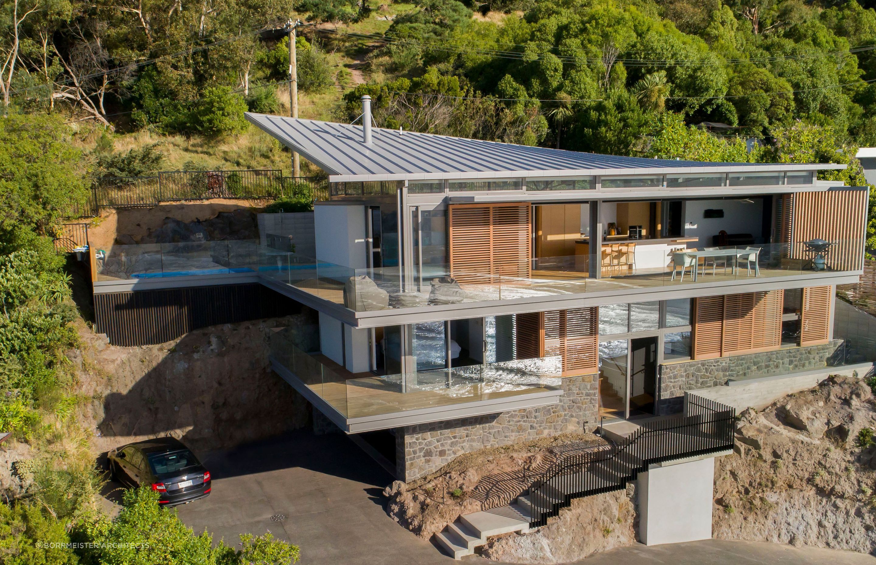 Red Rock House by Borrmeister Architects was designed to provide shelter from the prevailing winds, incorporate natural cross ventilation, solar panels, rainwater retention tanks and an ultra-low emission logburner.