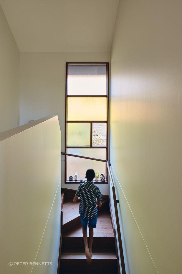 Coloured glass within the stairway and kitchen windows, along with a skylight shaft bathing the home’s entry in warm light, introduces zesty oranges, greens, reds and yellows into daily life.