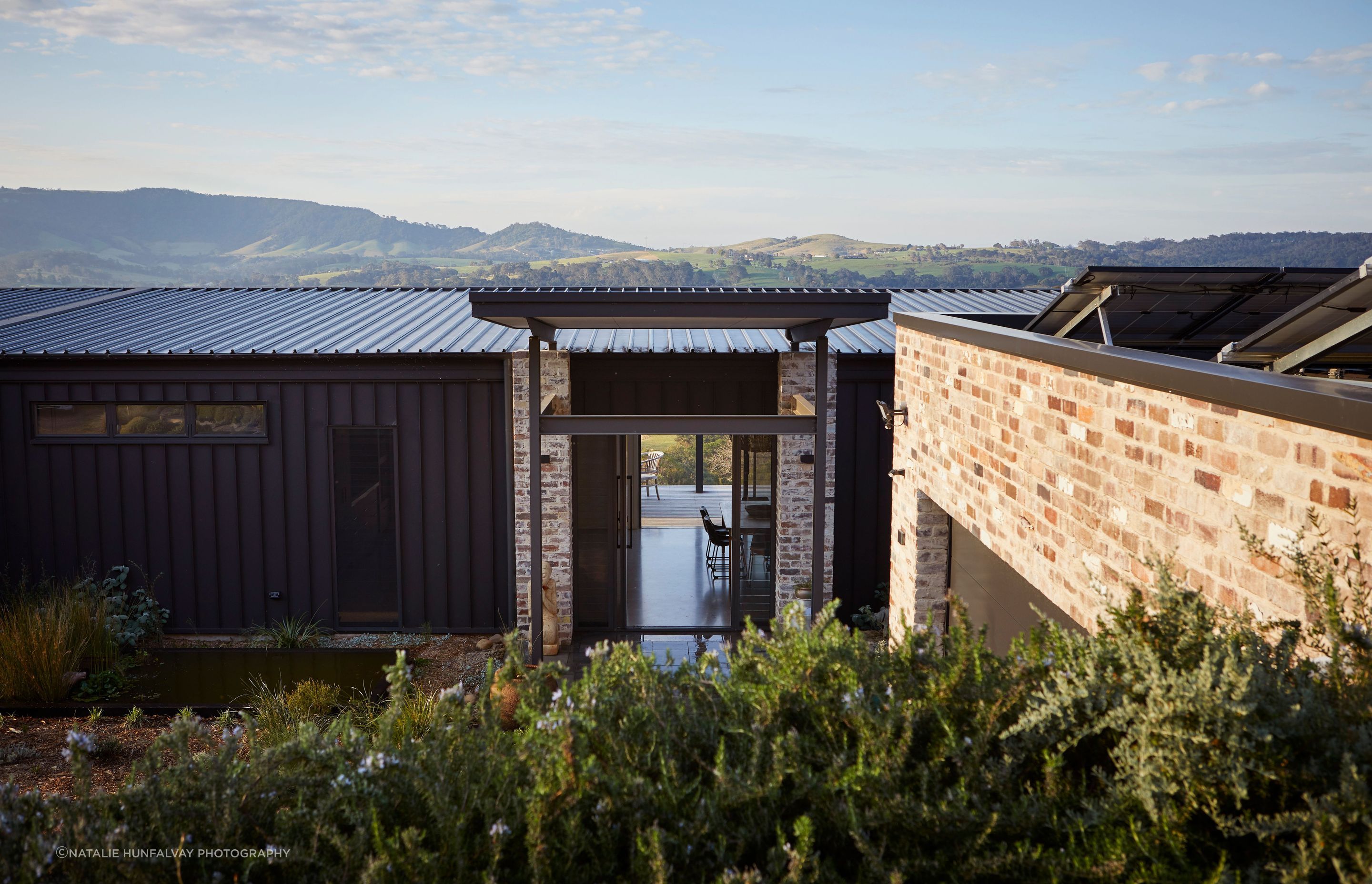 Solidified in black cladding and recycled brick to reflect the home’s surrounding grounds and uninterrupted views.