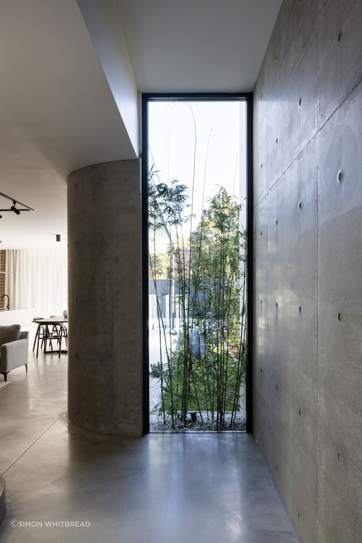 A floor to ceiling window displaying greenery lightens the polished concrete.