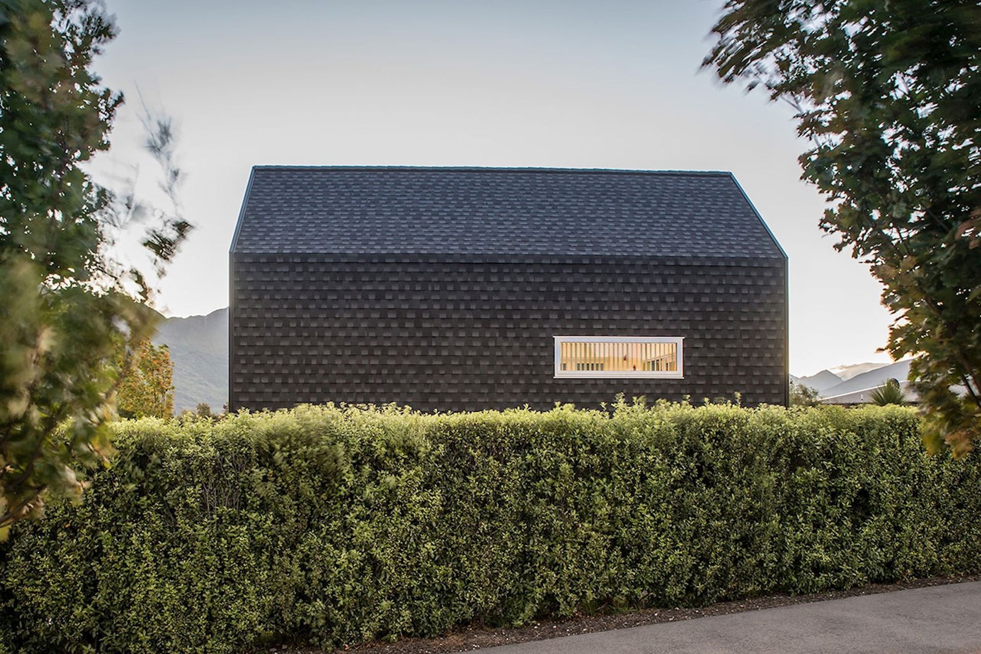 A bold kerbside view from across the hedge of the Kimimoko House