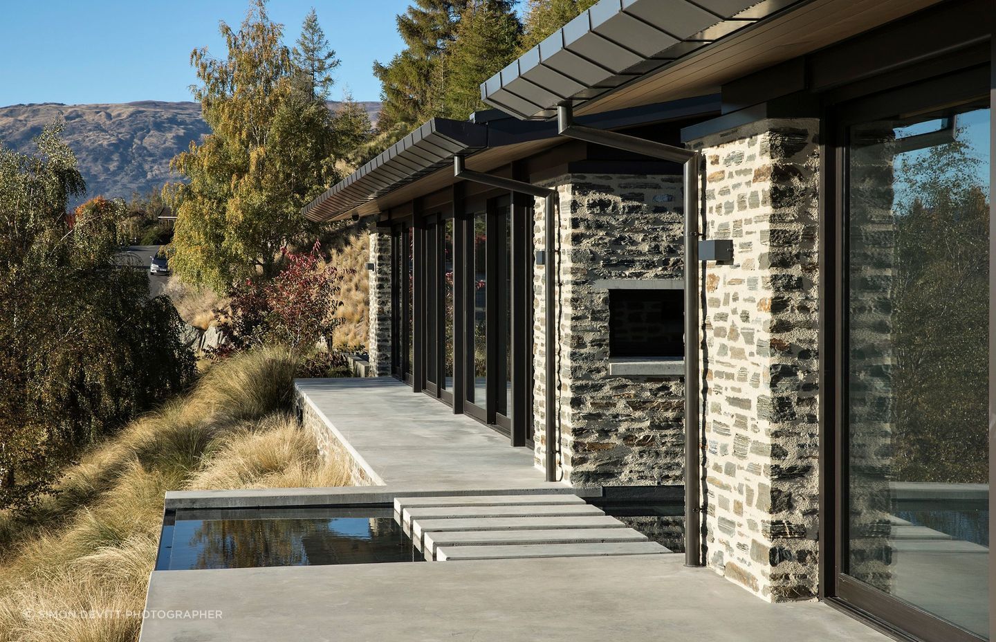 Constructed in local schist, Mt Aspiring House, by Mason &amp; Wales Architects, pays homage to the jaw-dropping views of Lake Wanaka and The Remarkables through full-height glazing and this linking pond between forms. Photograph by Simon Devitt.
