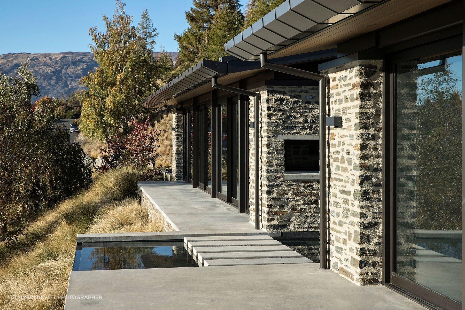 Constructed in local schist, Mt Aspiring House, by Mason & Wales Architects, pays homage to the jaw-dropping views of Lake Wanaka and The Remarkables through full-height glazing and this linking pond between forms. Photograph by Simon Devitt.