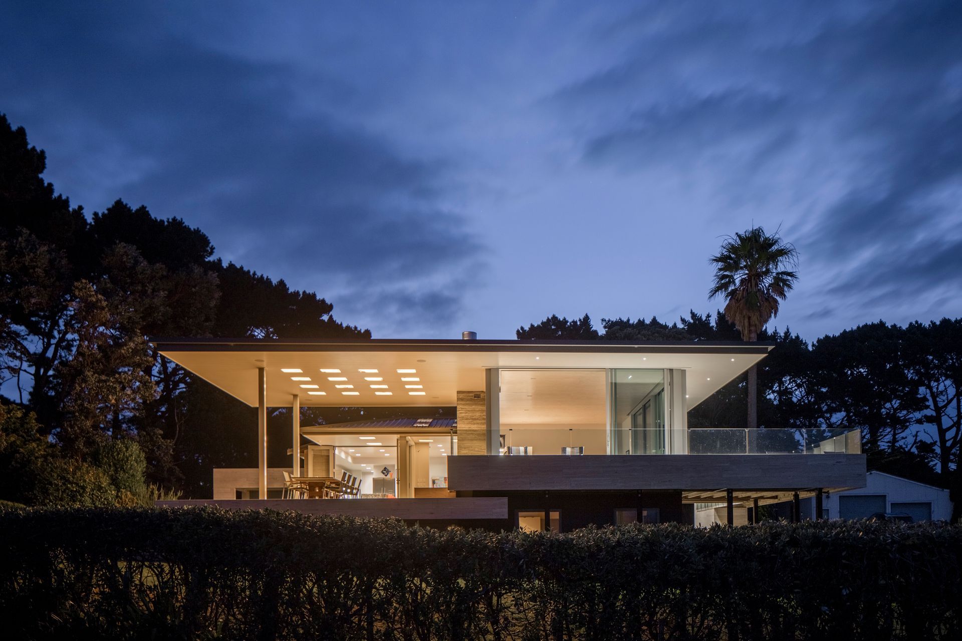 Northland Lake House by RB Studio features a 'hovering' roof punctured with square light wells diffused by honey-coloured translucent onyx stone slabs that provide a glowing ambient light at night.