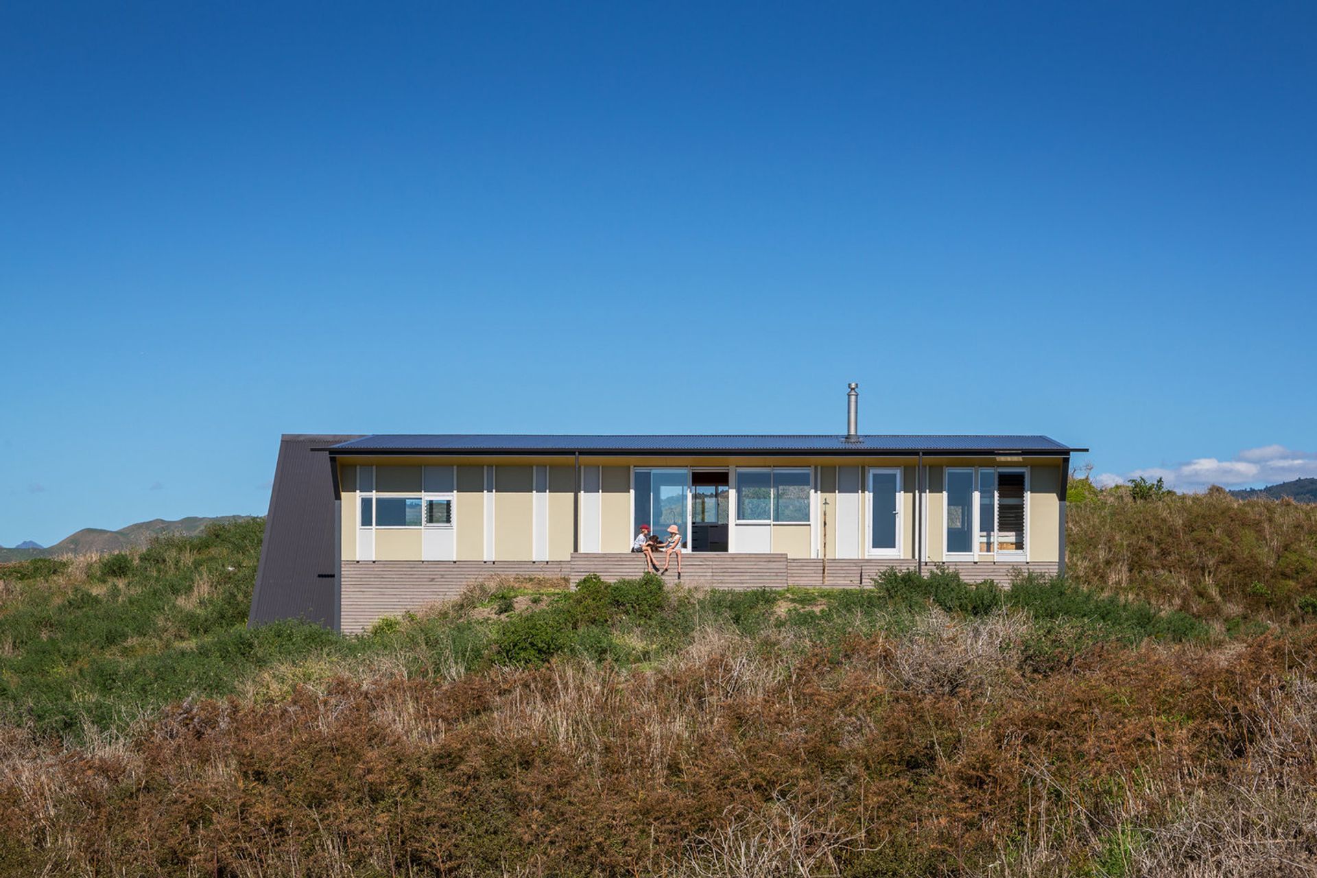 Te Horo Bach by Parsonson Architects is a small economically planned fibro and batten-clad building that has its design roots partly in the New Zealand bach tradition, with an explorative use of form, colour and material. Photograph by Paul McCredie.