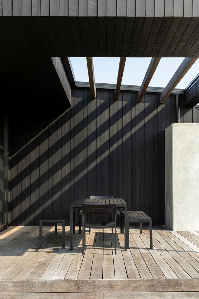 At Vineyard House, shadows from the overhead louvres stripe the timber wall of the outdoor room.