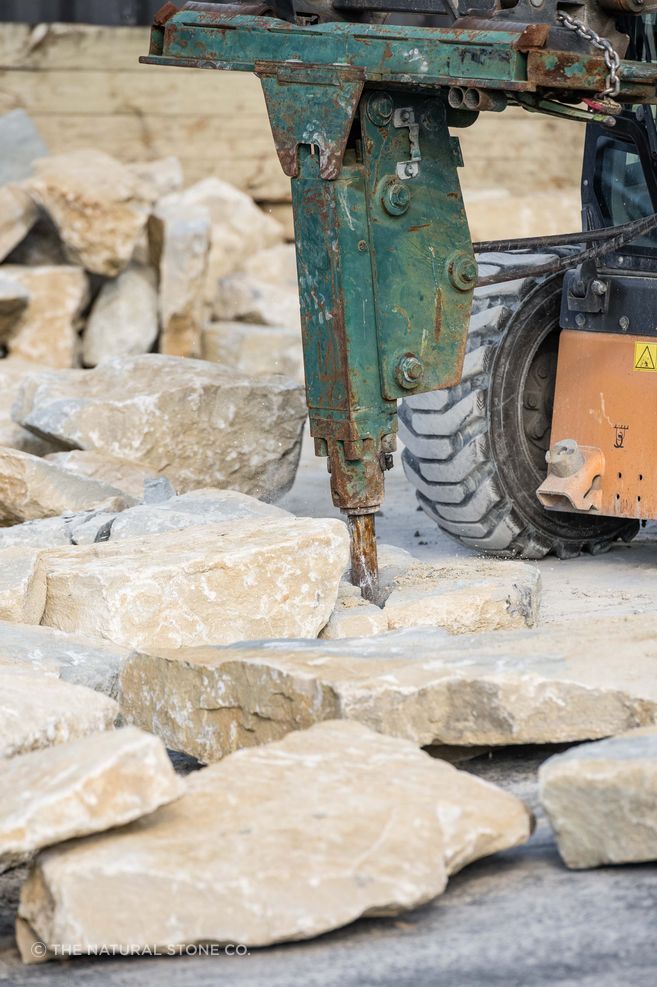 Breaking down limestone boulders at The Natural Stone Co.’s Tauranga premises, part of the practical process of turning raw stone into usable architectural elements.