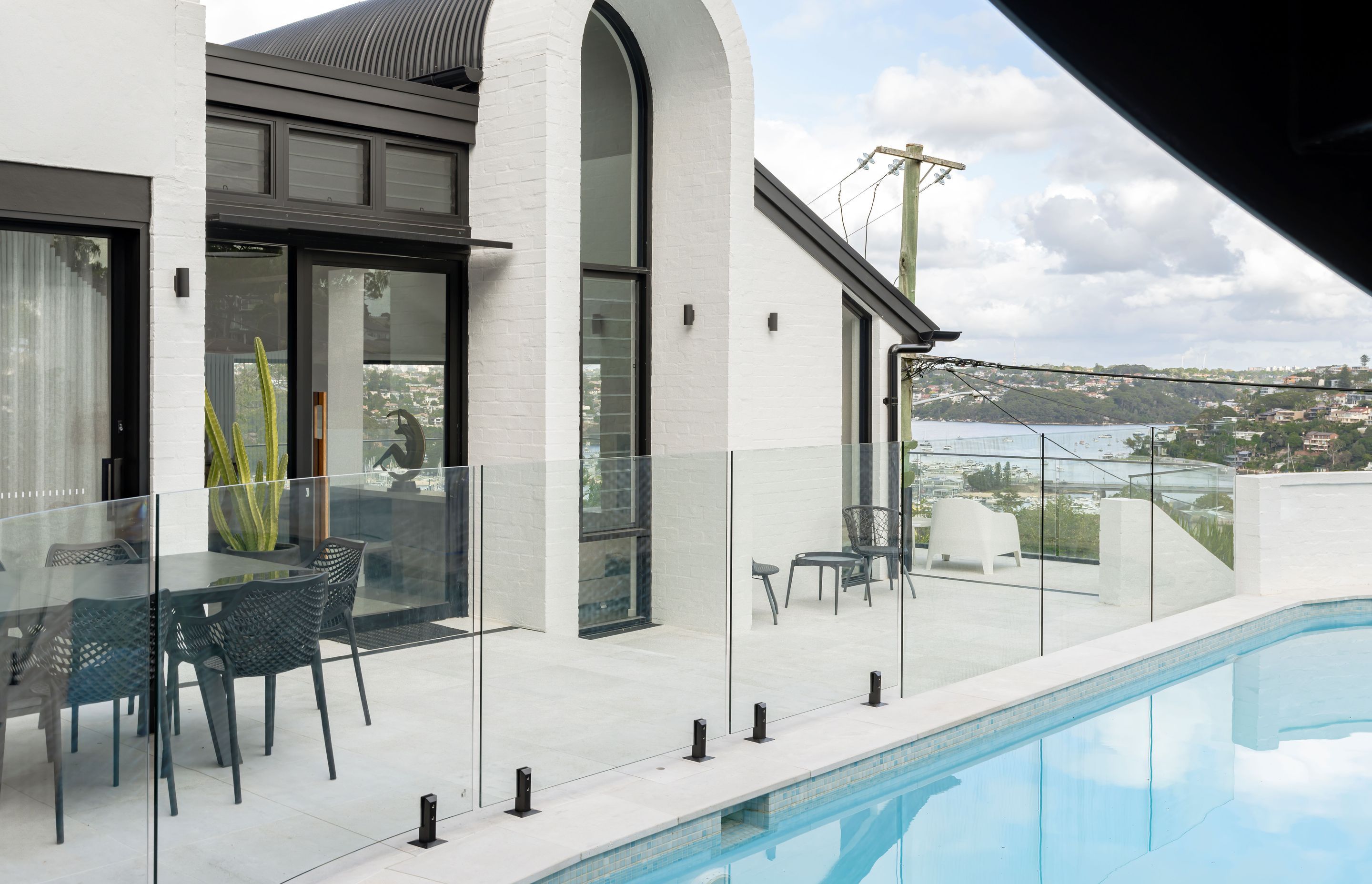 The strong monochromatic statement of this home is reflected in the pool glazing and black hardware by Glazed Co.