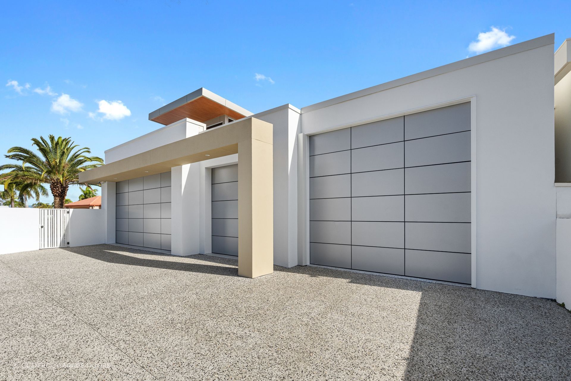 This custom garage door with aluminium composite panels ties in seamlessly with the home's material palette.