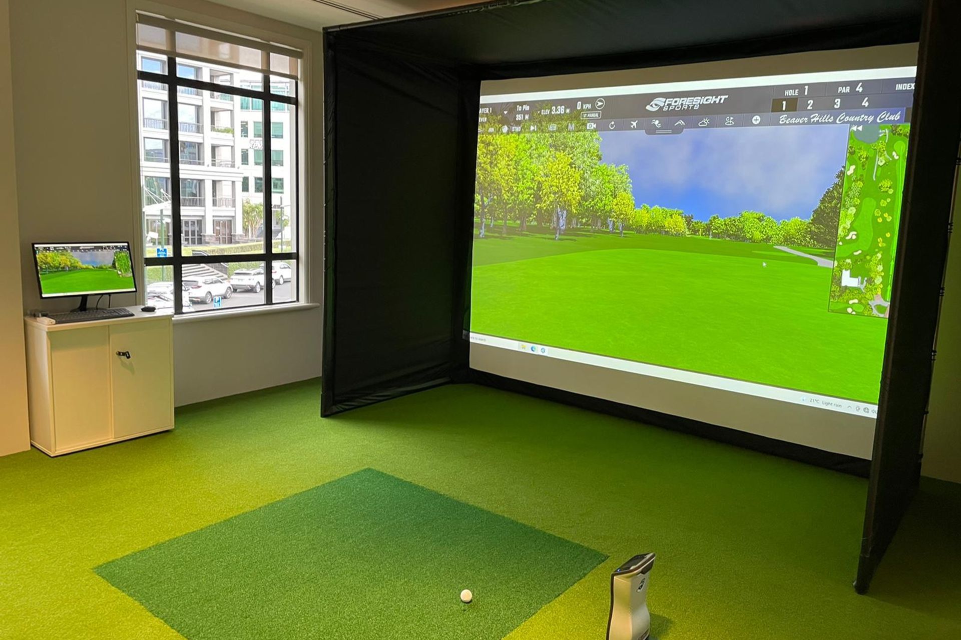 A Premium Golf Simulator with custom turf with a popup enclosure for this board room.