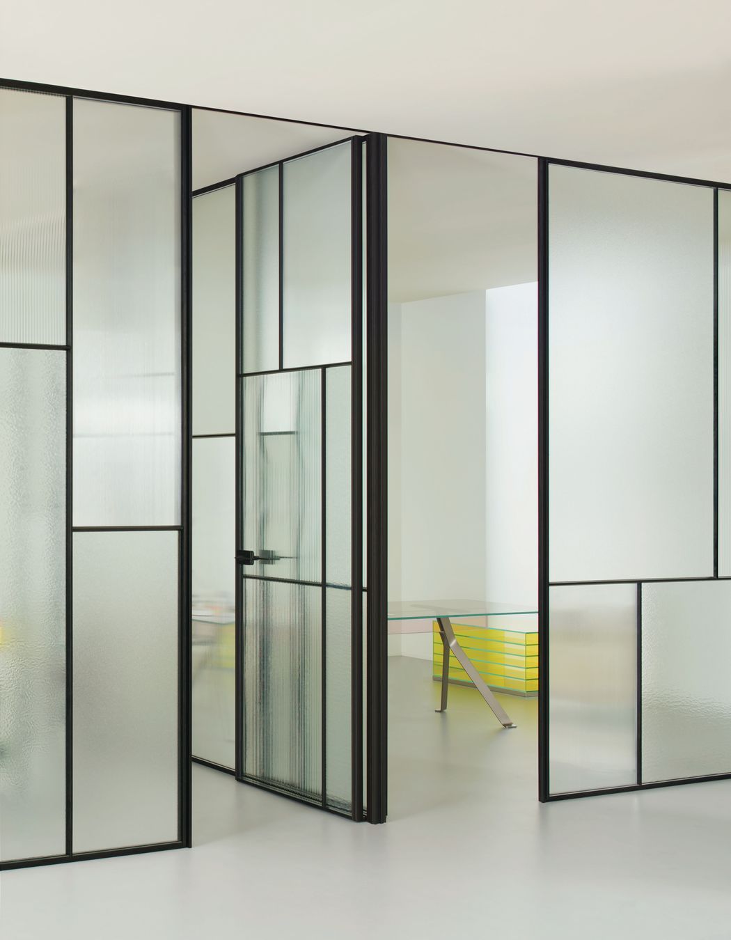 The Glas Italia Sherazade Wall Patchwork is a floor-to-ceiling partition wall made by juxtaposing and fixing panels divided into four squares through a click system, featuring different types of monolithic tempered glass.
