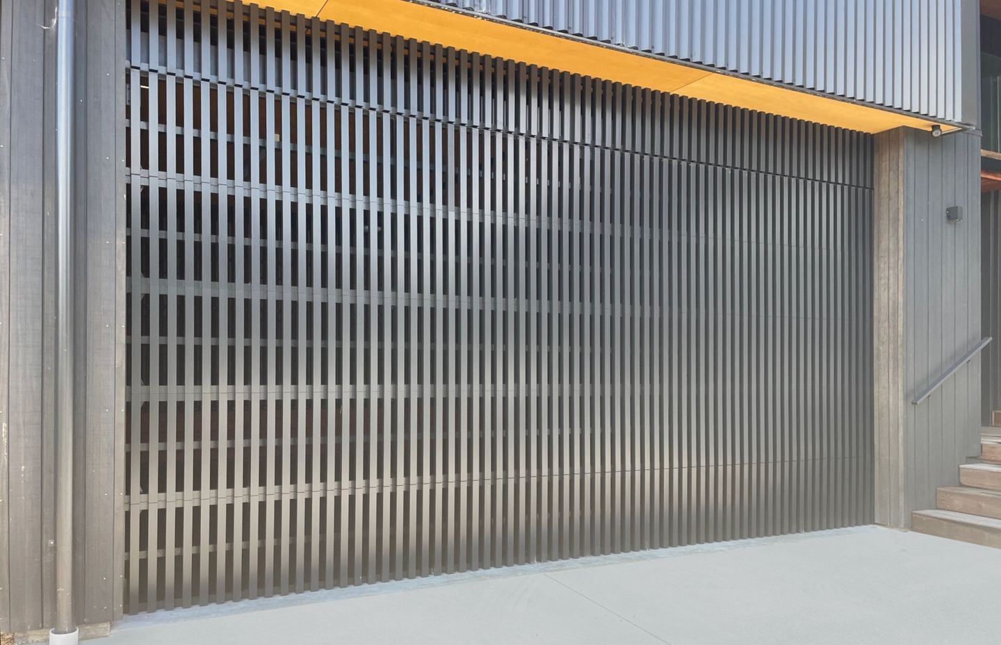 A custom batten ventilated garage door installed at a workshop in Whangamatā.