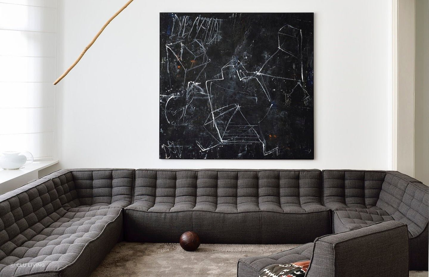 A clear white wall and distinct wall art provide a great backdrop to this dark grey corner sofa. Featured product: N701 Sofa Corner.