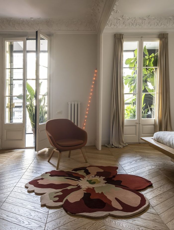 The Flora Bloom 2 rug by Nanimarquina features a distinctive design that adds both comfort and visual interest atop the hardwood floor