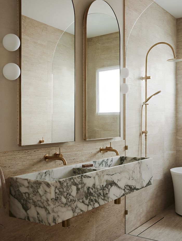 In the bathroom, bold stone elements contrast against brass and curves for a truly high-end feel.