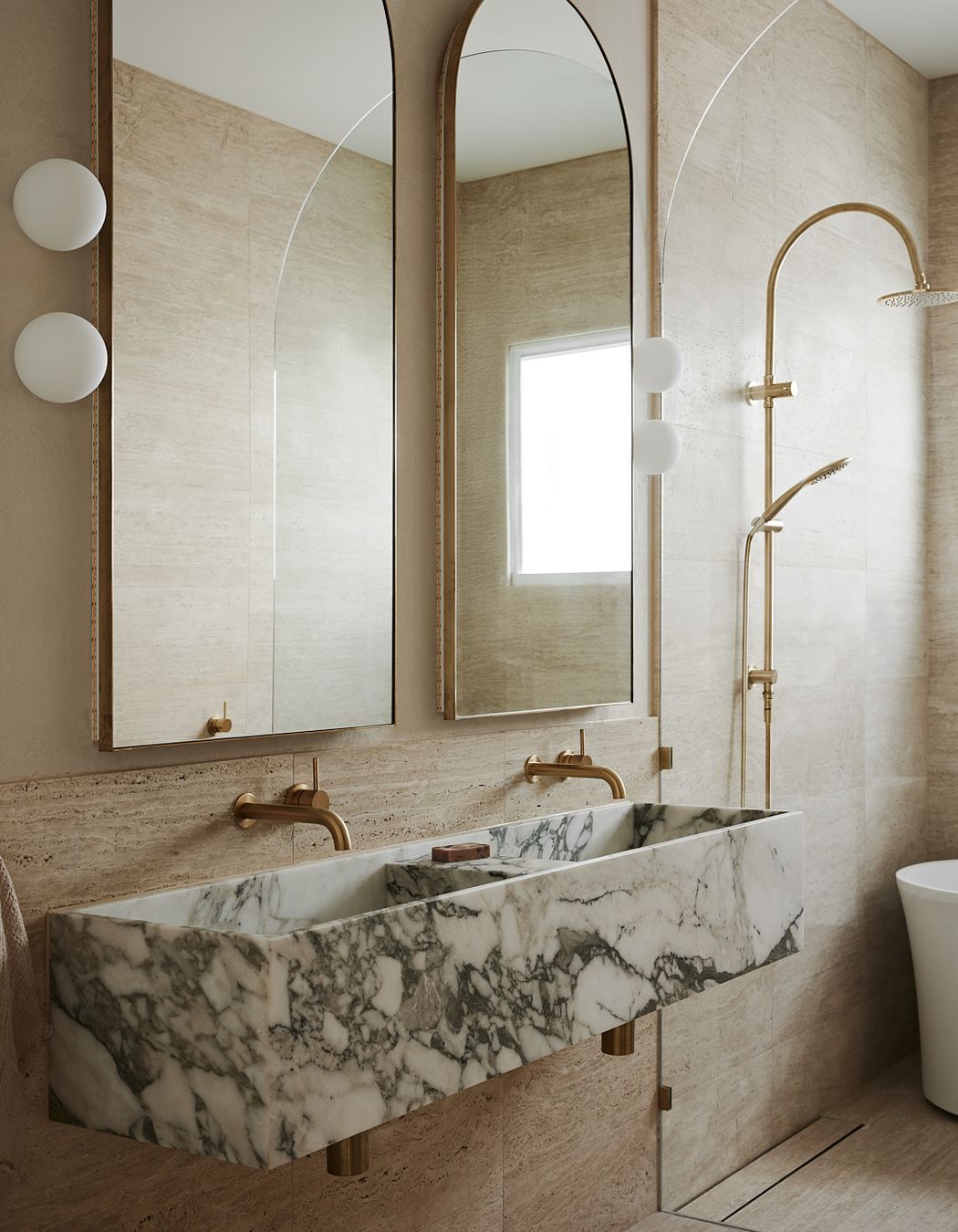In the bathroom, bold stone elements contrast against brass and curves for a truly high-end feel.