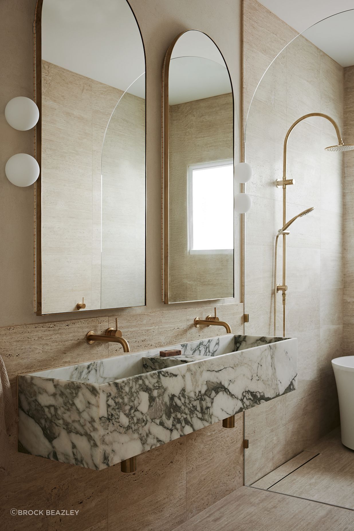 In the bathroom, bold stone elements contrast against brass and curves for a truly high-end feel.