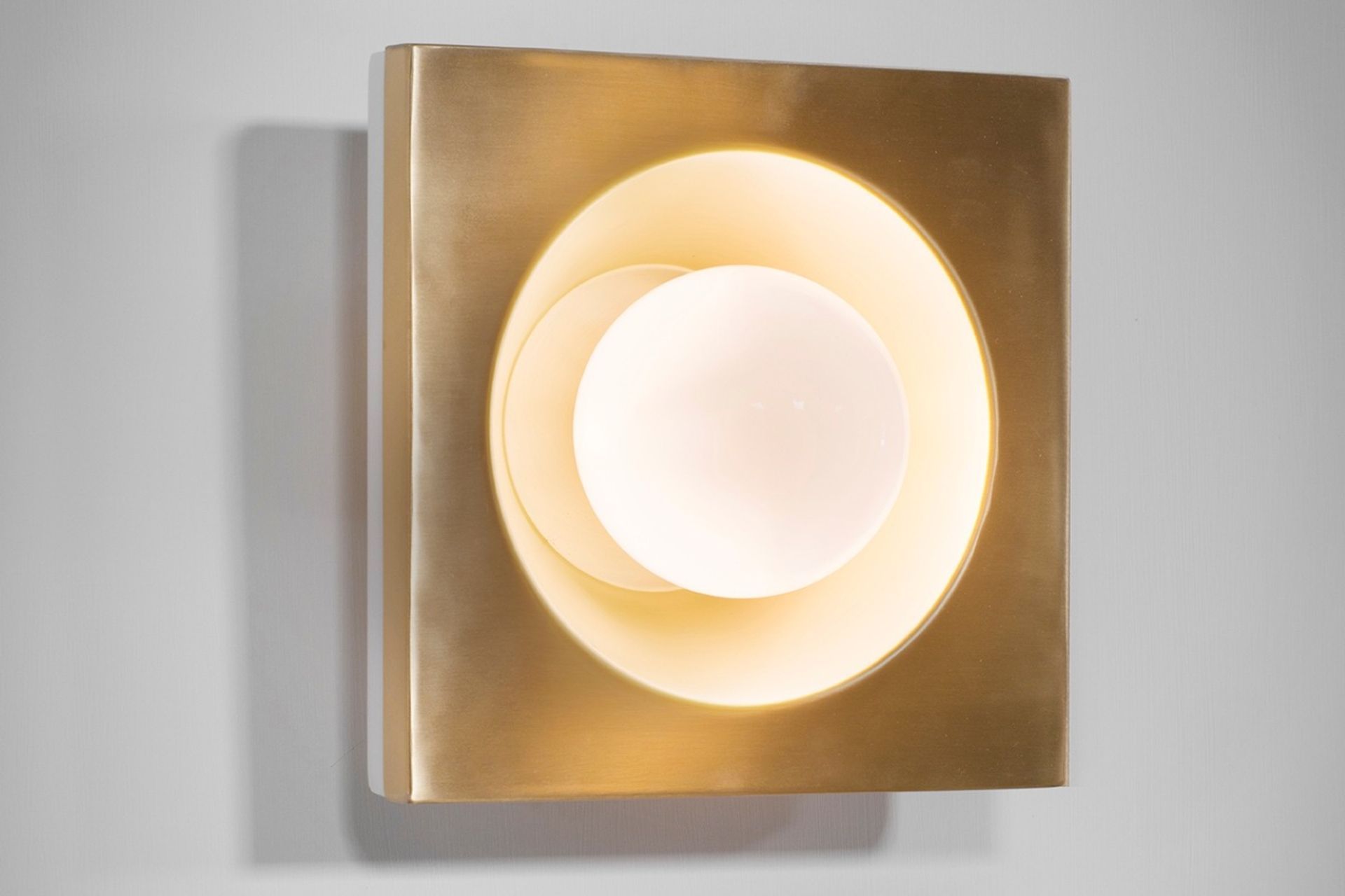 The Kins Wall Light and its warm Brass lacquered metal finish.