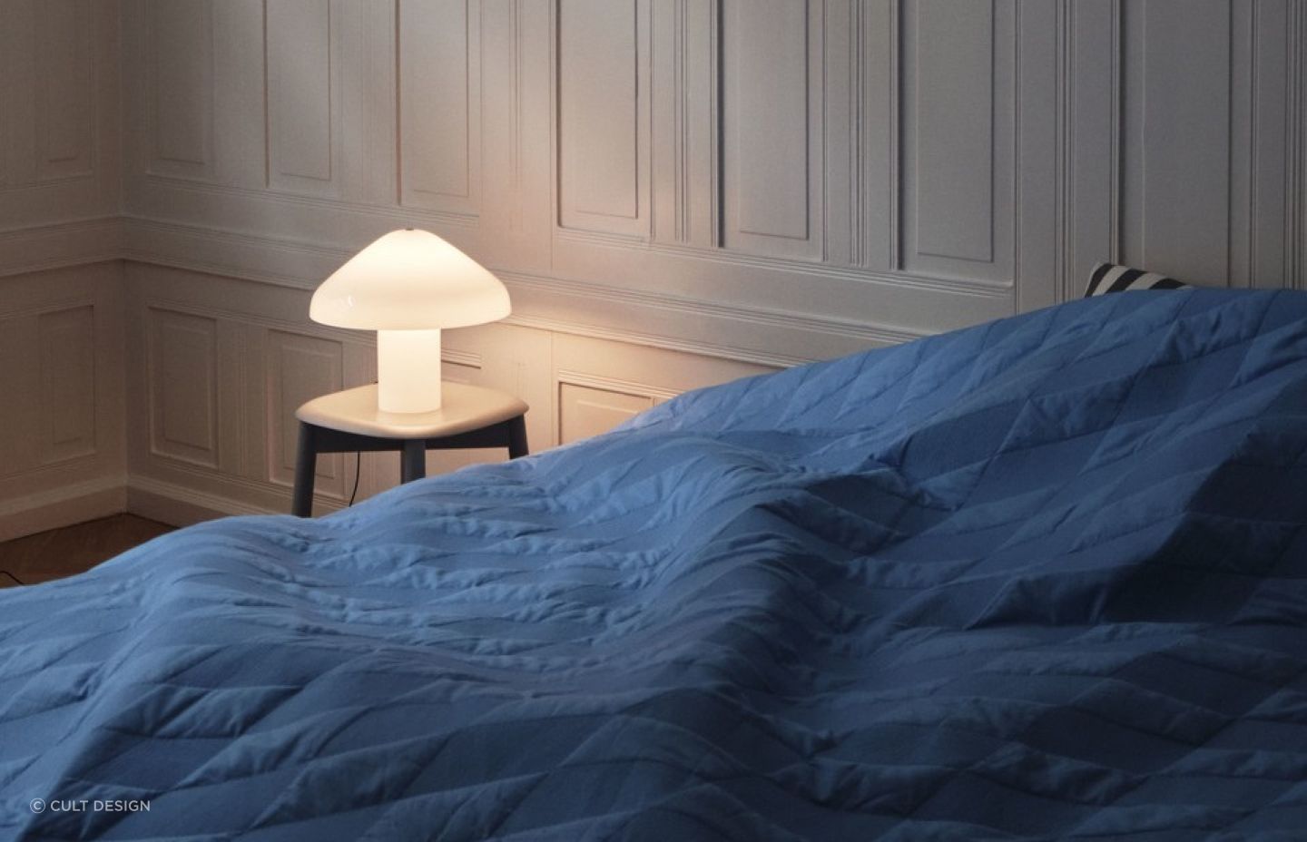 A bedside table can set the stage for a designer lamp like the Pao Glass Table Lamp by HAY.