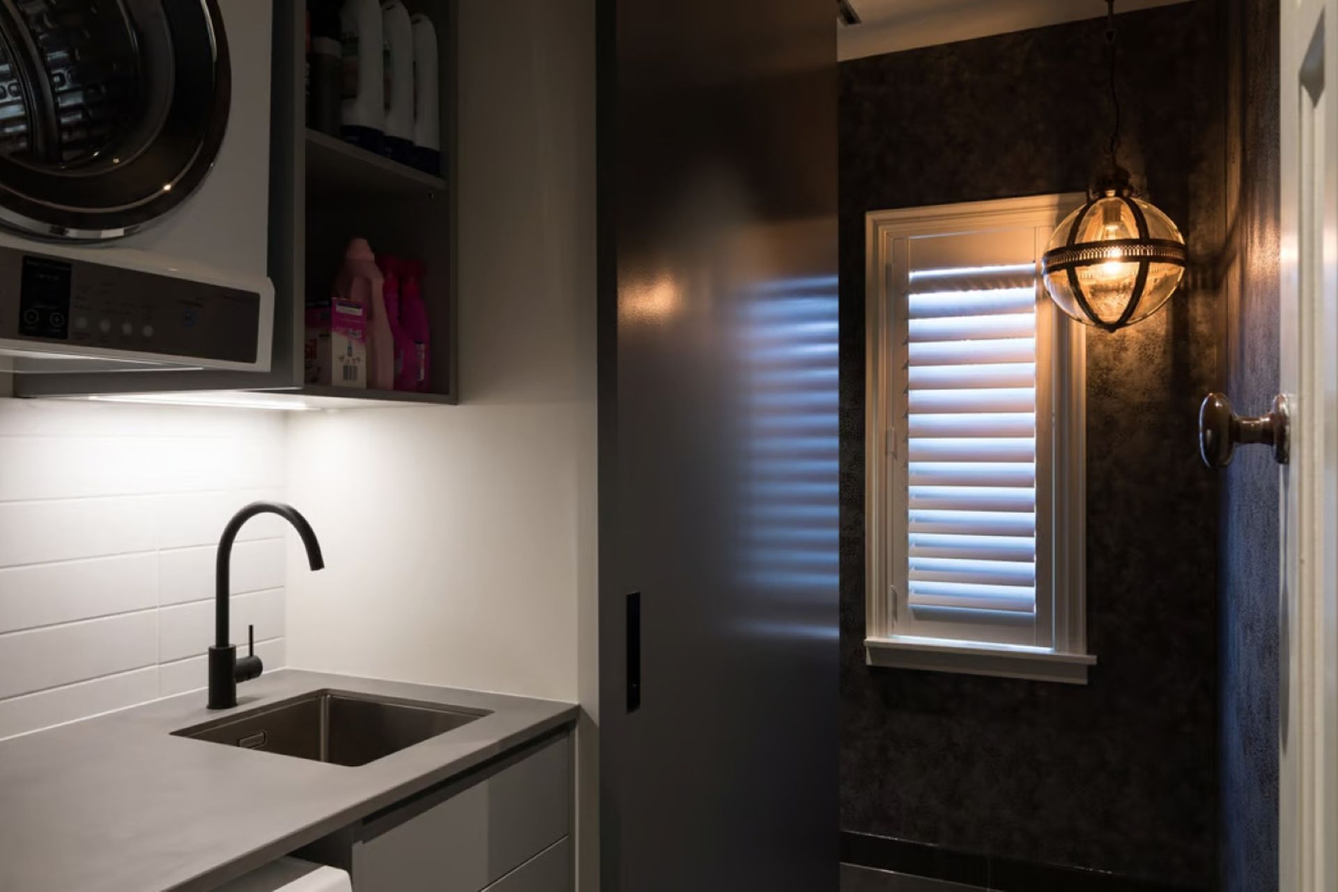 This designer pendant light sets a bold and unique mood in this stylish laundry room designed by Nicola Manning Design.