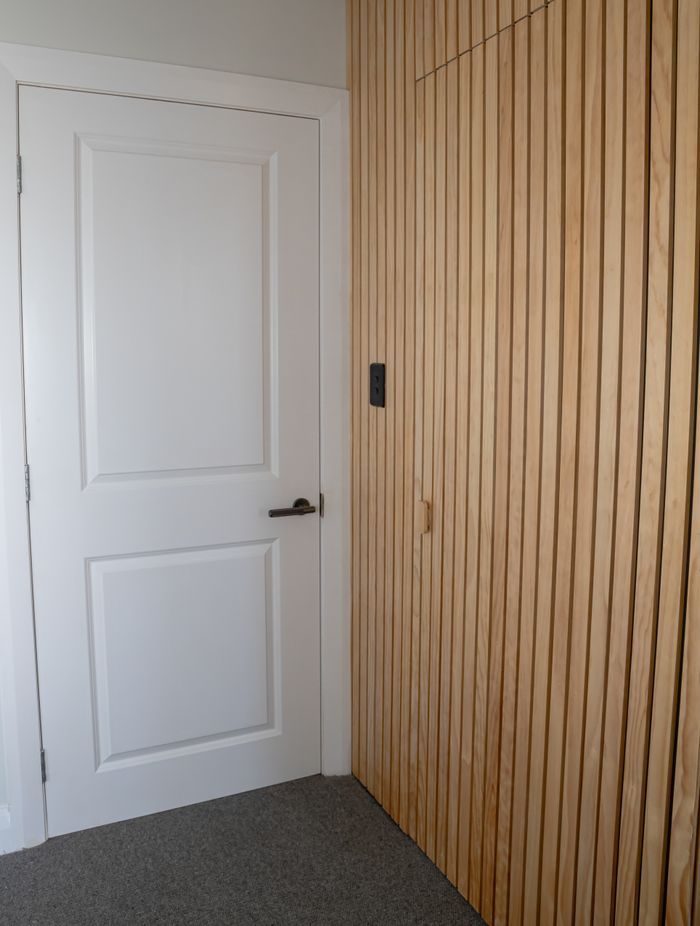 The timber batten wall conceals the doorway to the walk-in wardrobe and ensuite.