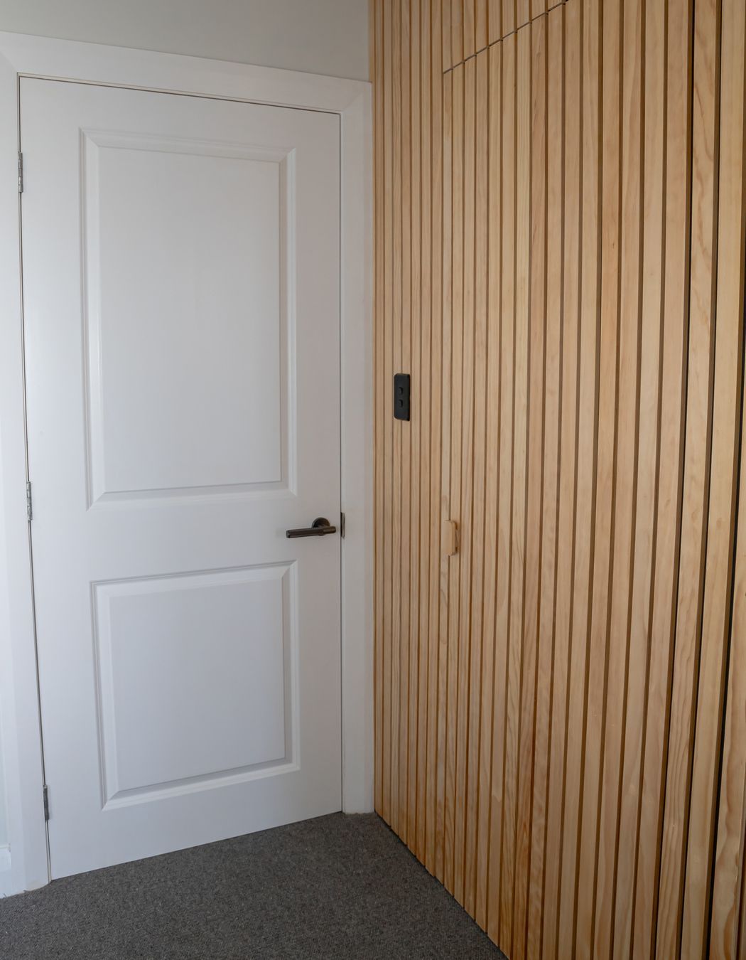 The timber batten wall conceals the doorway to the walk-in wardrobe and ensuite.