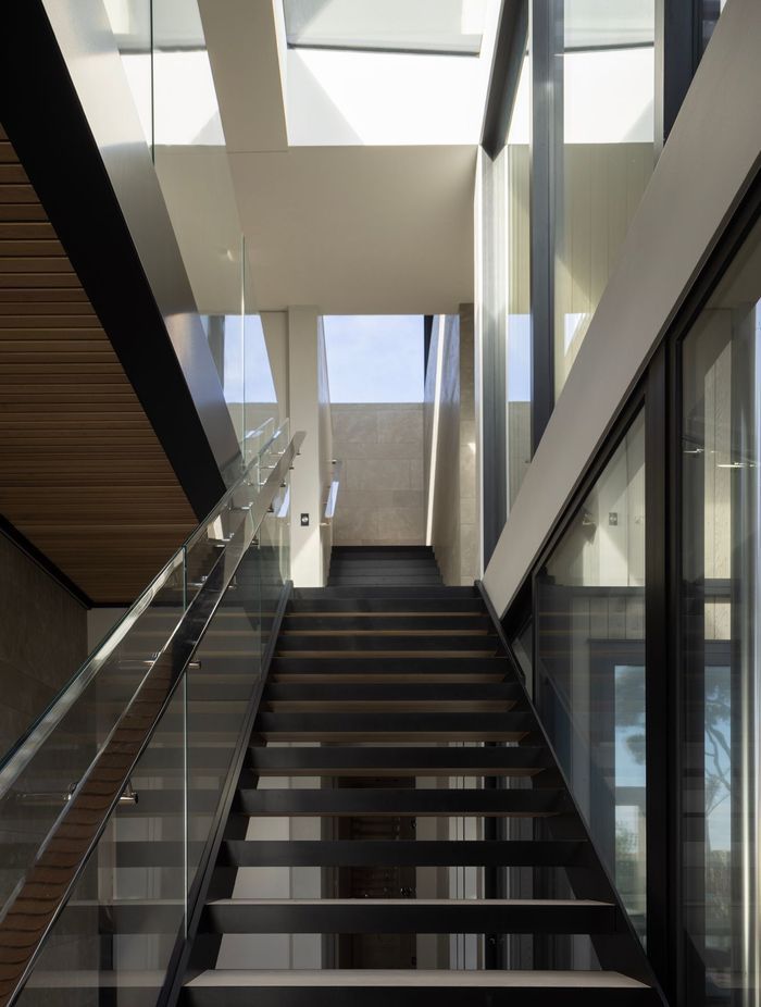 At Pohutukawa House, the journey down two sets of stairs tempts visitors down to the main living space on the bottom floor.