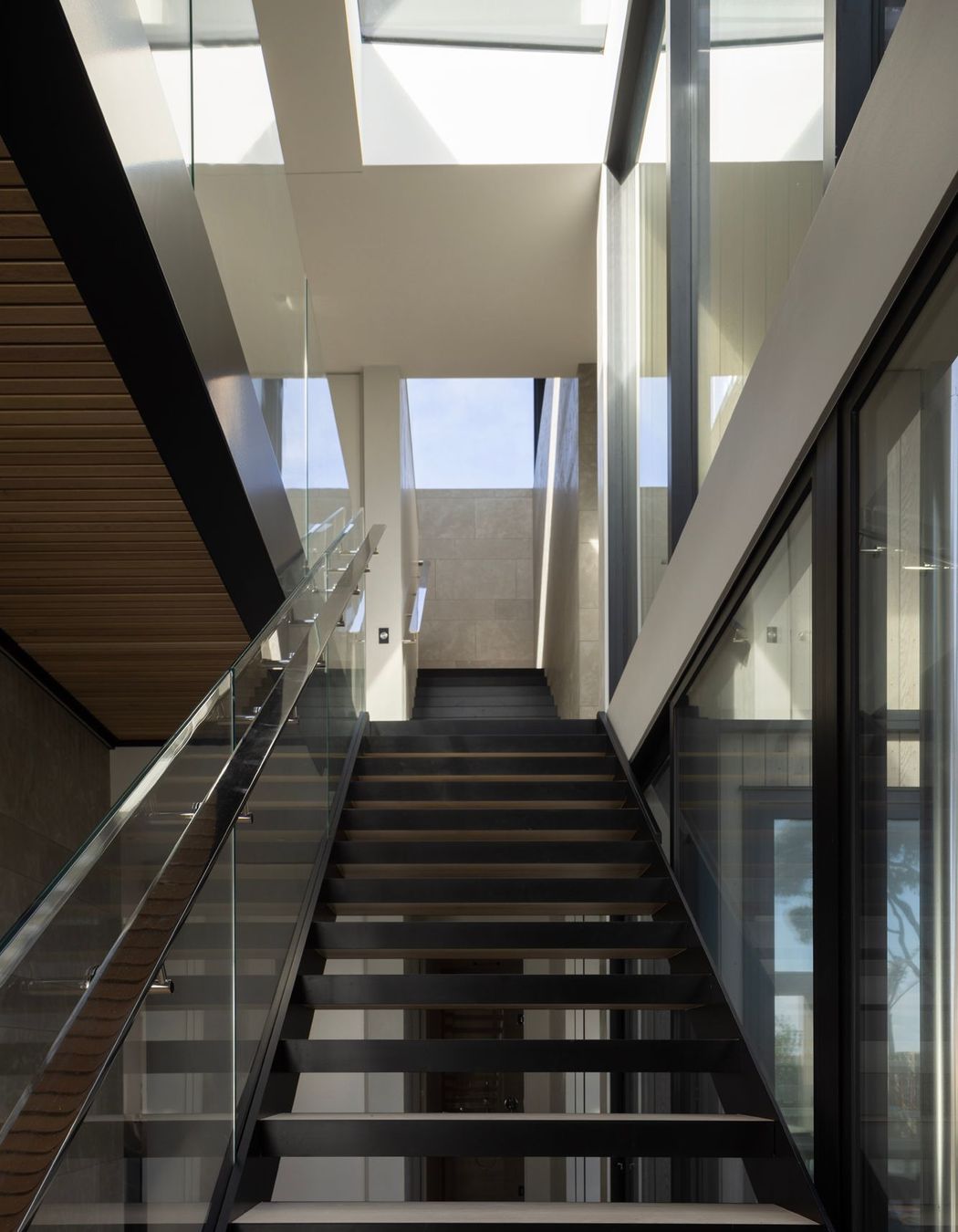 At Pohutukawa House, the journey down two sets of stairs tempts visitors down to the main living space on the bottom floor.