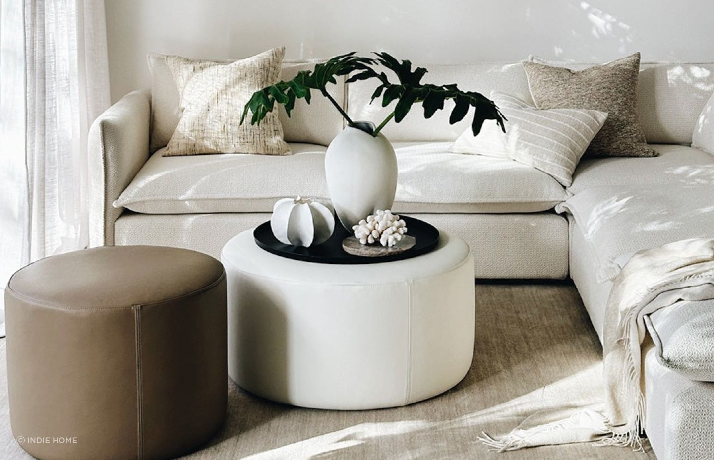 The 'Rio' Ottoman in Cream Leather from Indie Home sets a great stage for decorative pieces.