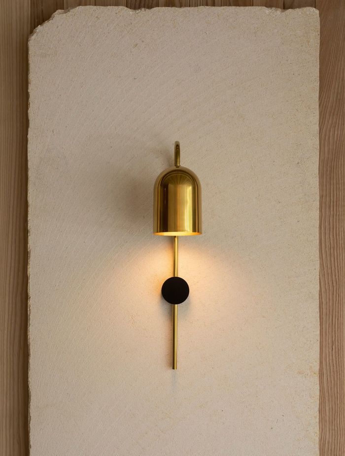 A sleek golden sconce illuminates the natural beauty of the limestone.