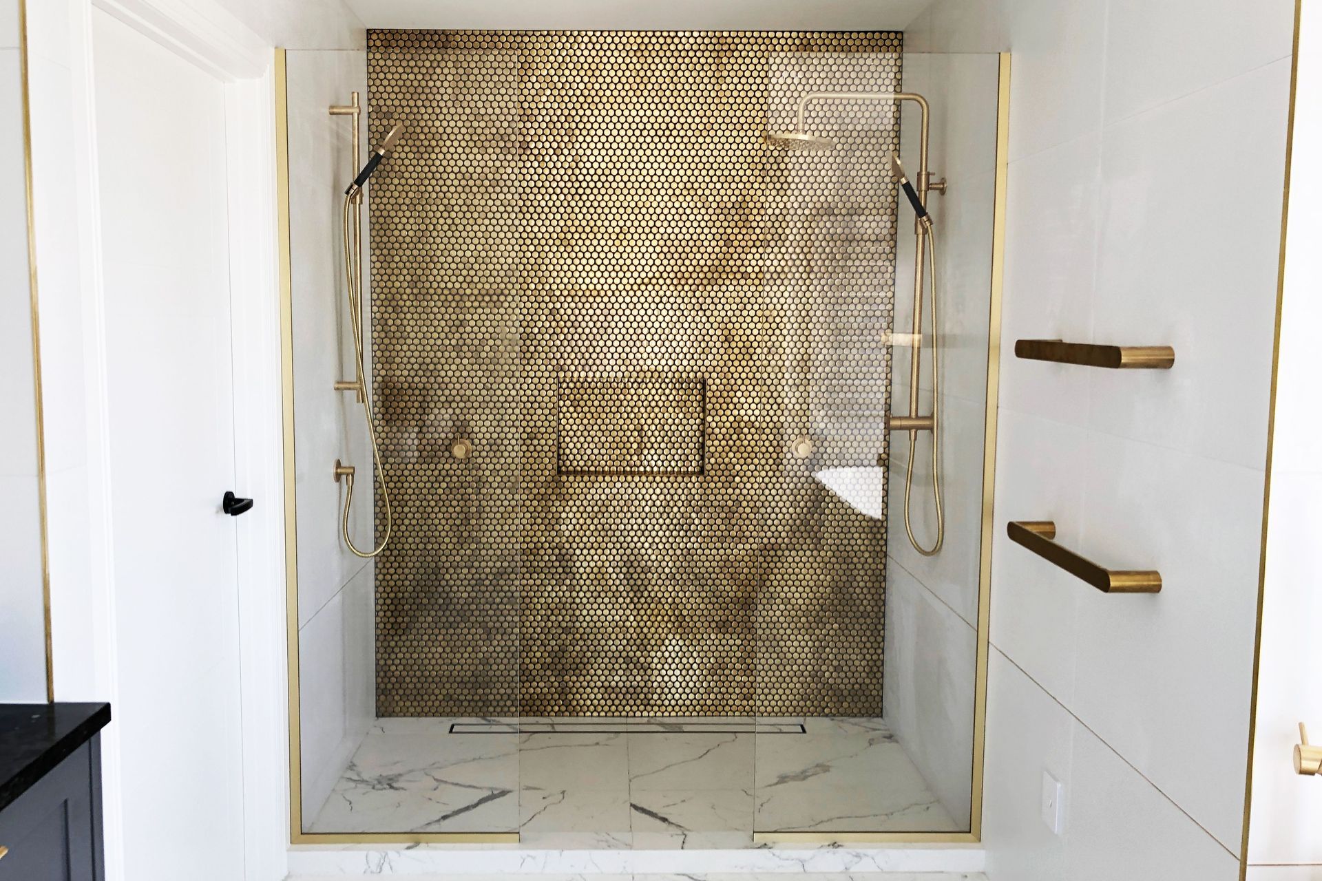 This fixed panel shower glass features gold hardware to match other gold fixtures in the bathroom.