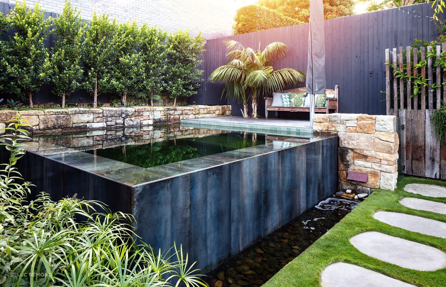 A square natural pool extruded from the ground in lush surroundings by Land Forms. | Photography: Luc Remond